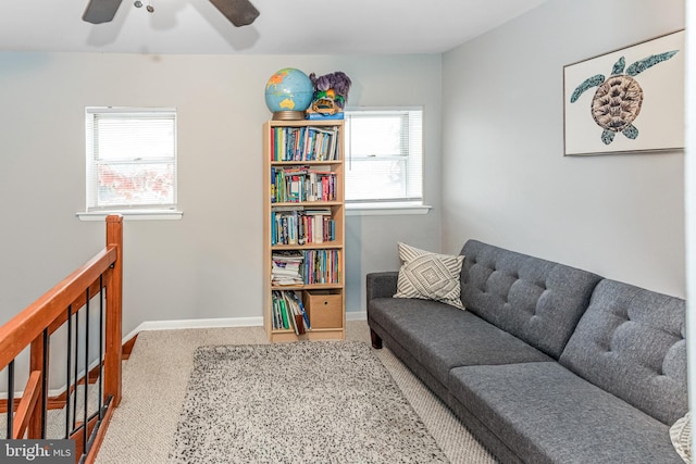 sitting room with a healthy amount of sunlight, carpet, baseboards, and an upstairs landing