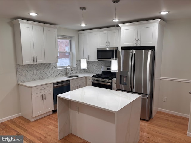 kitchen with sink, white cabinetry, light stone counters, decorative light fixtures, and stainless steel appliances