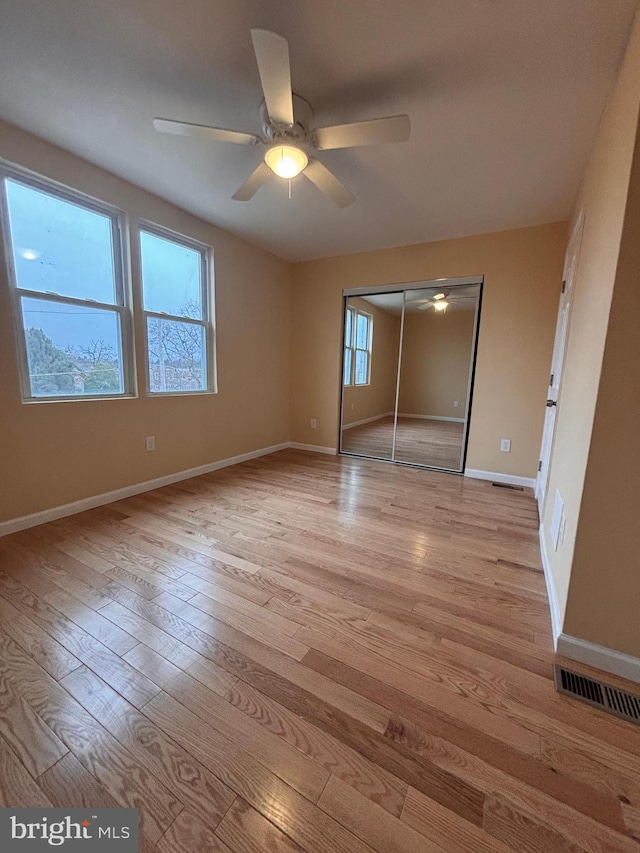 unfurnished bedroom featuring ceiling fan, a closet, and light wood-type flooring