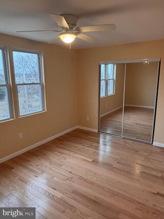 unfurnished bedroom featuring ceiling fan, a closet, and light hardwood / wood-style flooring