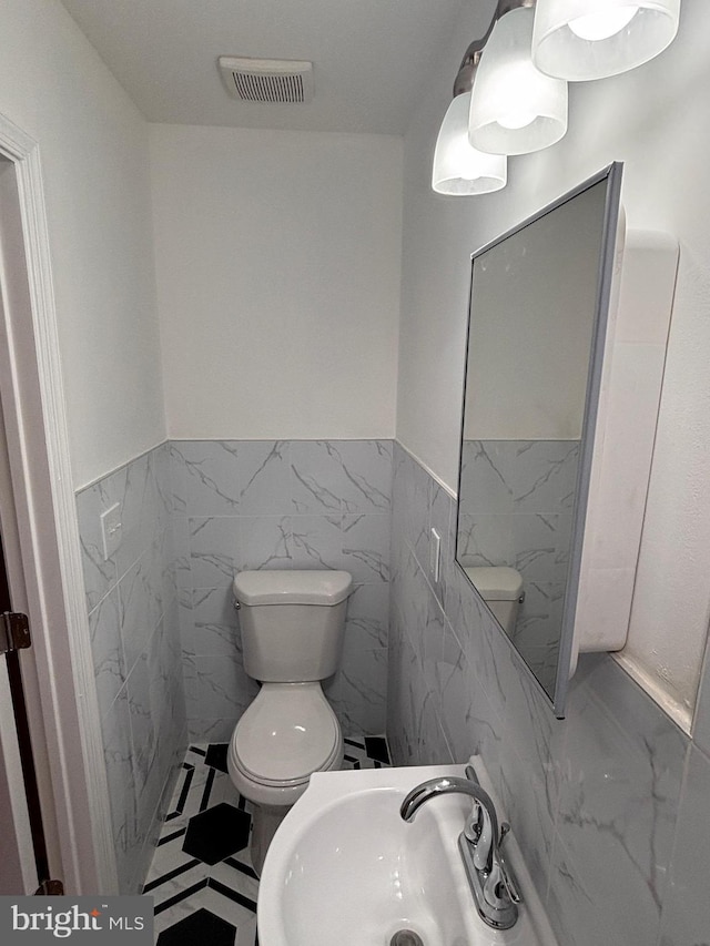 bathroom featuring toilet, sink, and tile walls