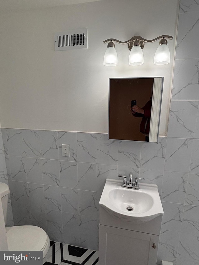 bathroom featuring vanity, tile walls, and toilet