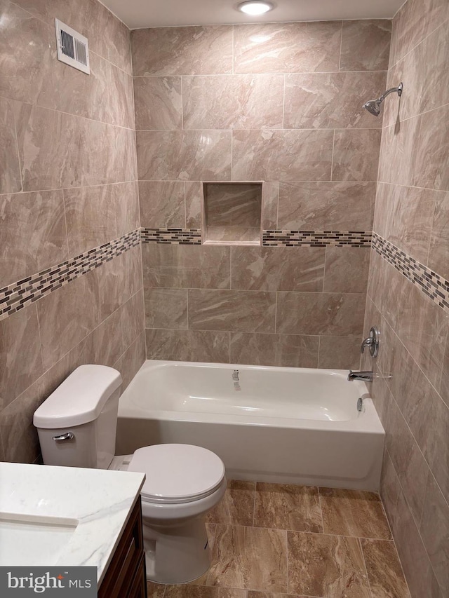 full bathroom featuring tiled shower / bath, tile walls, vanity, and toilet