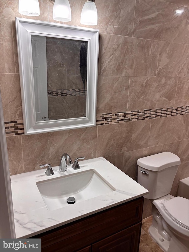 bathroom featuring vanity, backsplash, tile walls, and toilet