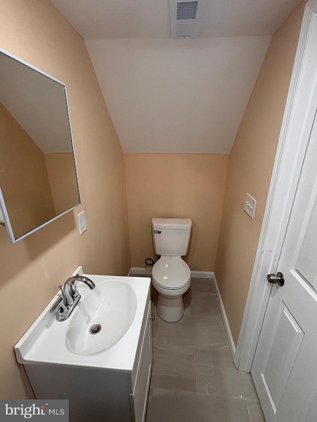 bathroom featuring vanity, vaulted ceiling, and toilet