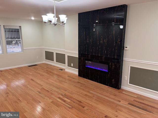 empty room with hardwood / wood-style flooring and a notable chandelier