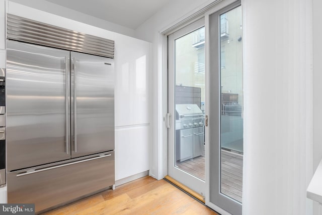 kitchen with built in refrigerator and light hardwood / wood-style flooring