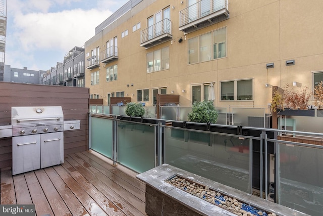 wooden deck featuring area for grilling, exterior kitchen, and a fire pit