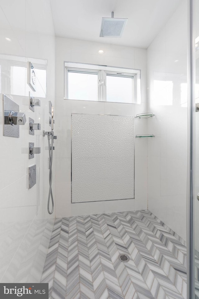 bathroom featuring a tile shower and a healthy amount of sunlight