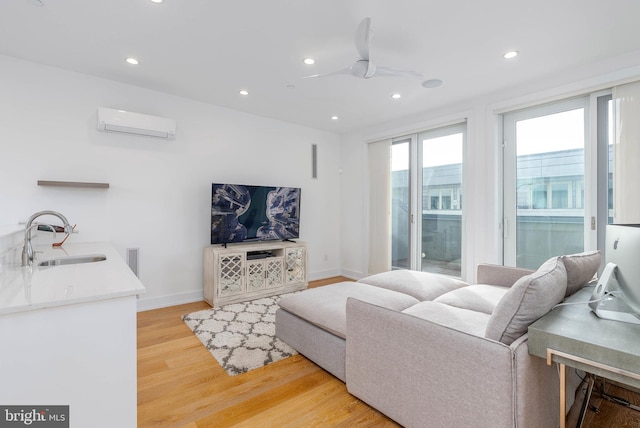 living room with sink, hardwood / wood-style flooring, an AC wall unit, and ceiling fan