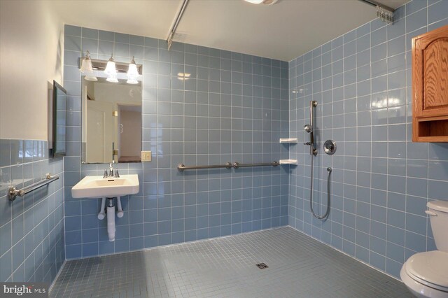 bathroom featuring tile patterned flooring, tiled shower, and tile walls