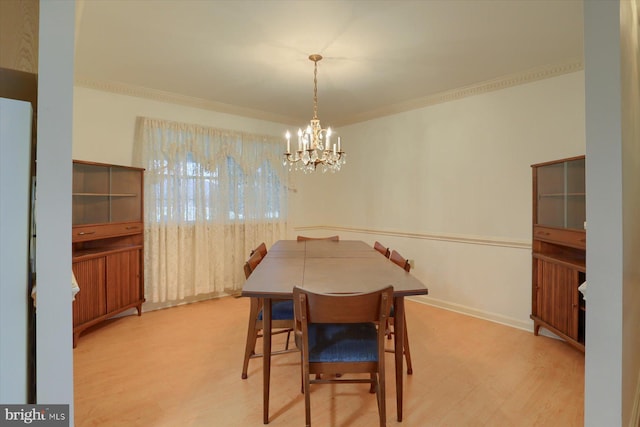 dining area featuring crown molding, an inviting chandelier, and light hardwood / wood-style flooring