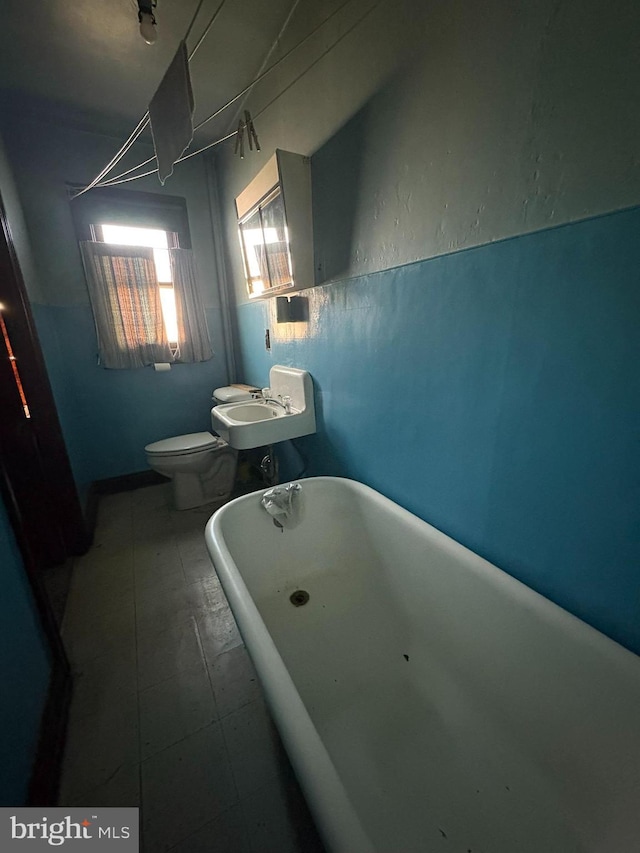 bathroom featuring sink, a bath, and toilet