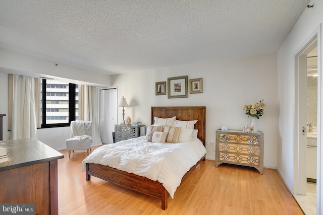 bedroom with a textured ceiling and light wood-type flooring