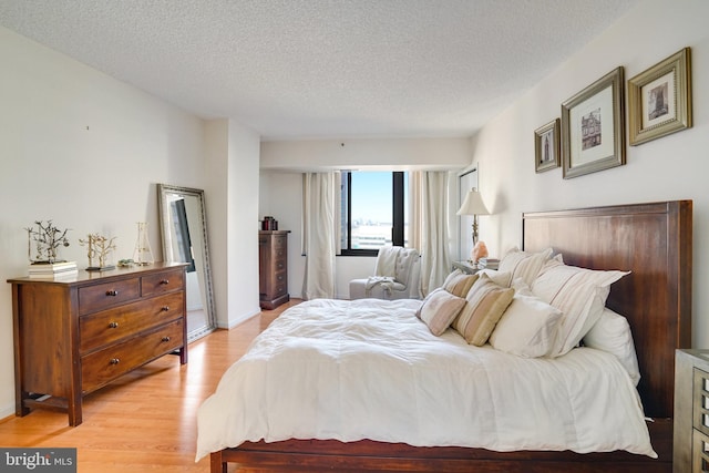 bedroom featuring a textured ceiling and light hardwood / wood-style flooring