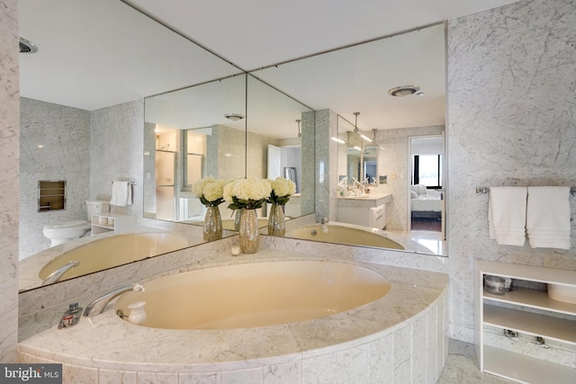 bathroom with vanity, tiled bath, tile walls, and toilet