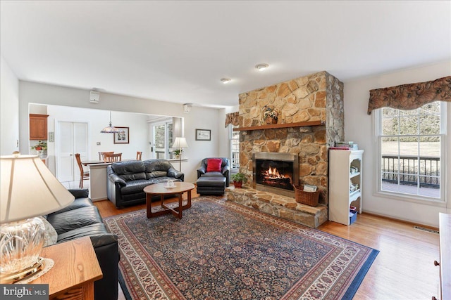 living room with a stone fireplace and light hardwood / wood-style flooring