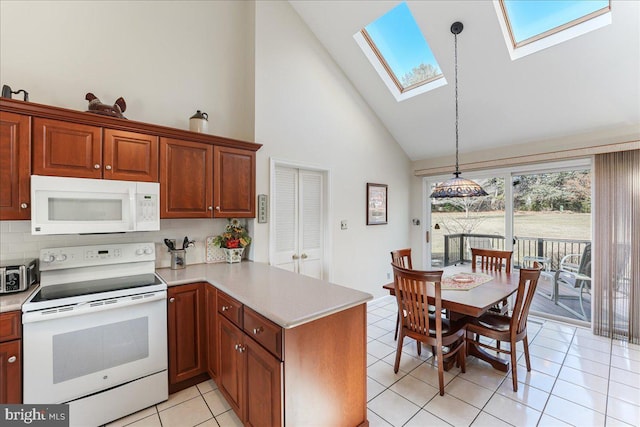 kitchen with white appliances, decorative light fixtures, kitchen peninsula, and a skylight