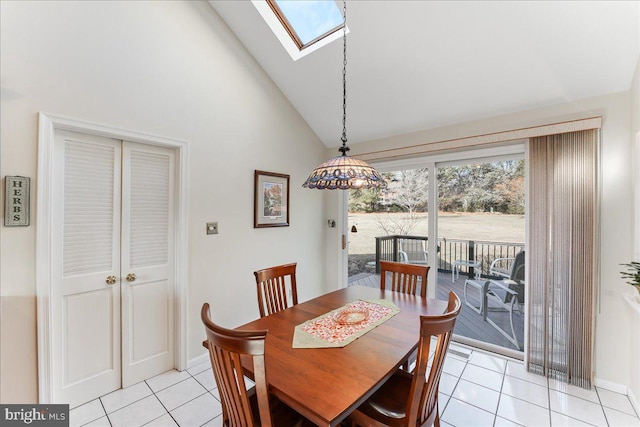 dining space with light tile patterned flooring, a skylight, and high vaulted ceiling