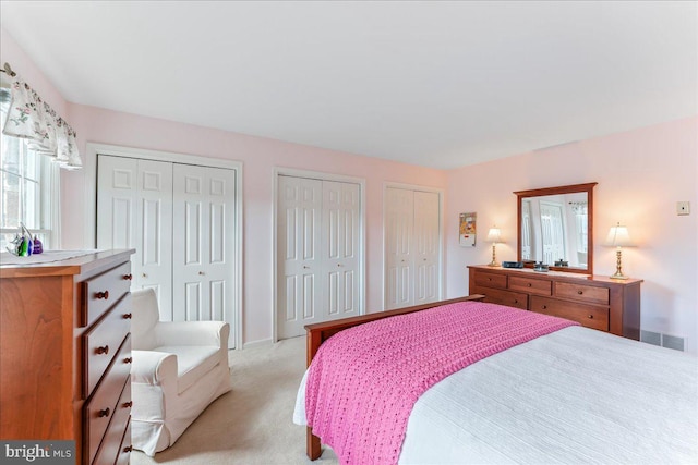 bedroom featuring light carpet and two closets