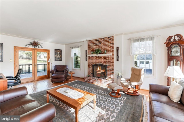 living room with hardwood / wood-style floors, a wealth of natural light, ornamental molding, and a brick fireplace