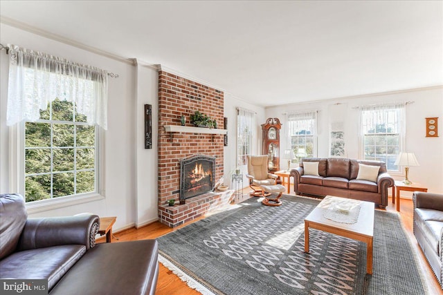 living room with crown molding, a brick fireplace, and hardwood / wood-style floors