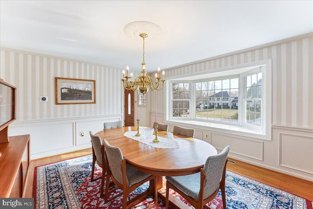 dining room featuring hardwood / wood-style flooring, ornamental molding, and a notable chandelier