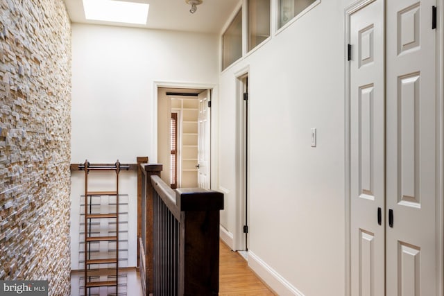 hall featuring a skylight and light hardwood / wood-style flooring