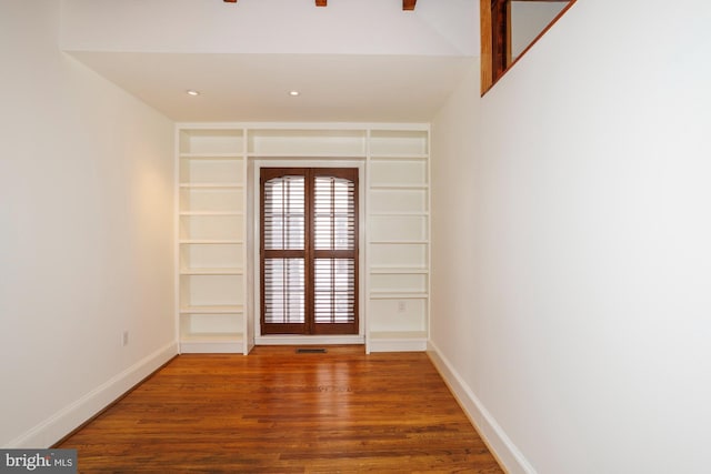 spare room featuring hardwood / wood-style flooring and built in features