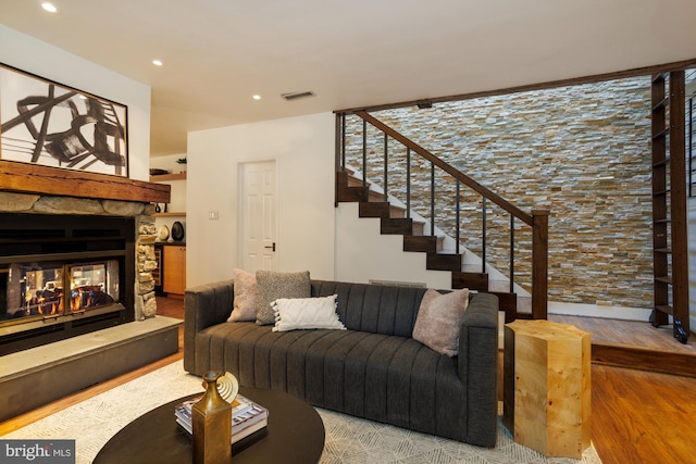 living room featuring a stone fireplace and hardwood / wood-style floors