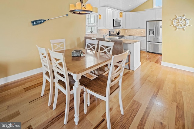 dining room featuring lofted ceiling and light hardwood / wood-style flooring