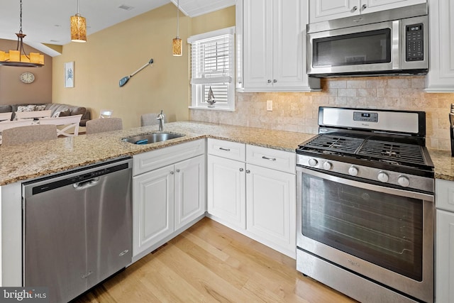 kitchen featuring sink, light hardwood / wood-style flooring, white cabinetry, stainless steel appliances, and decorative light fixtures