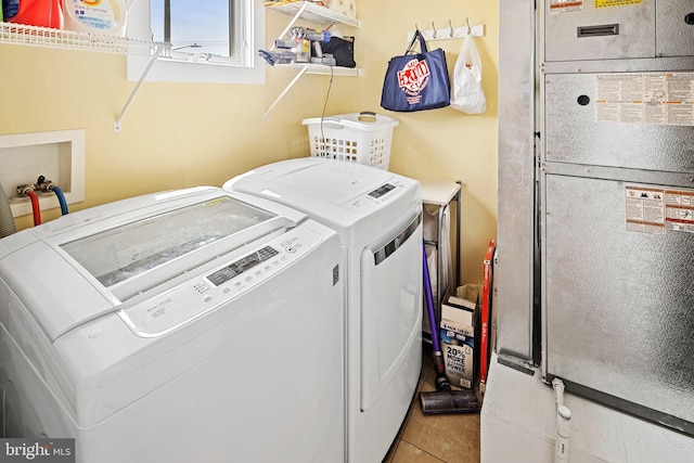 clothes washing area featuring heating unit, light tile patterned floors, and washing machine and clothes dryer