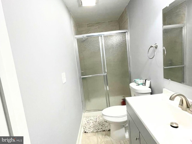 bathroom with a shower with door, vanity, and toilet