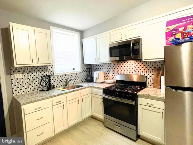 kitchen featuring tasteful backsplash, sink, light stone counters, and stainless steel appliances