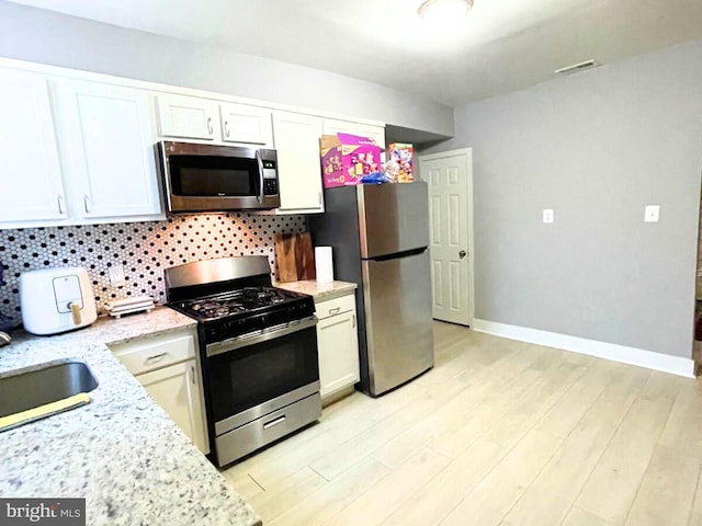 kitchen featuring appliances with stainless steel finishes, white cabinets, and decorative backsplash