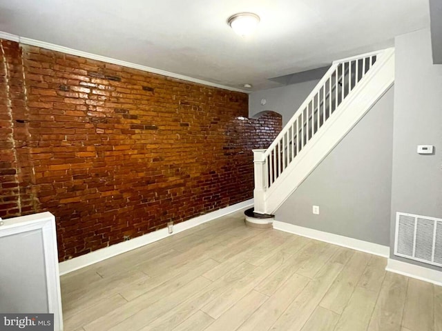 stairs featuring brick wall and wood-type flooring