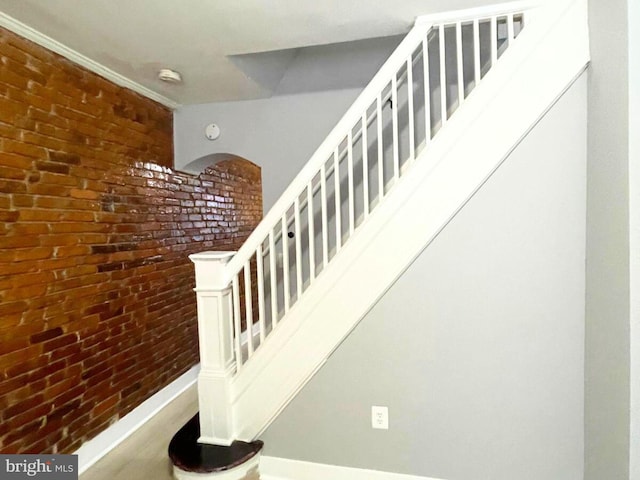 staircase featuring brick wall