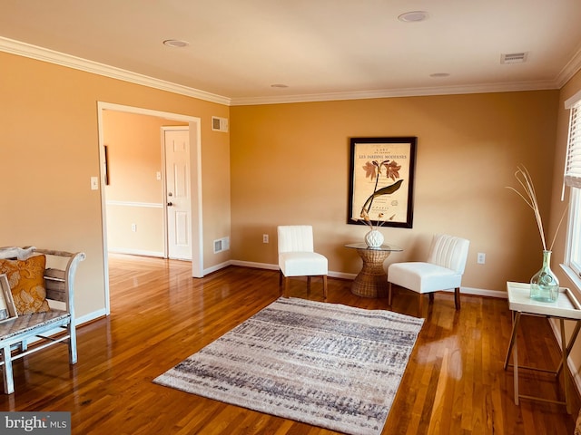 living area featuring ornamental molding, visible vents, baseboards, and wood finished floors