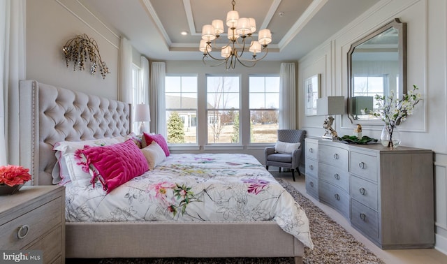 bedroom with a raised ceiling, ornamental molding, and a chandelier