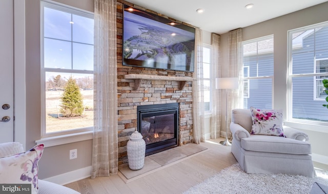 living room featuring a stone fireplace and light hardwood / wood-style floors