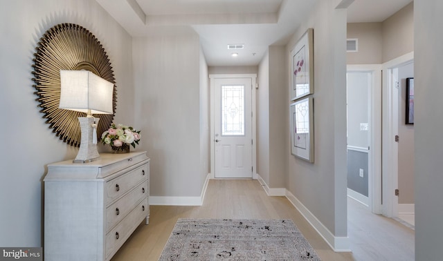 foyer with a tray ceiling and light hardwood / wood-style flooring