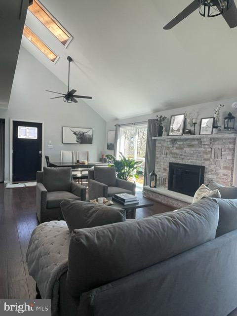 living room featuring a brick fireplace, dark hardwood / wood-style floors, high vaulted ceiling, and ceiling fan