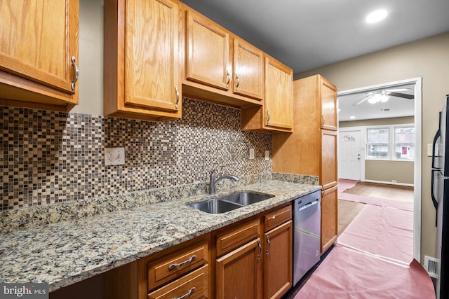 kitchen featuring tasteful backsplash, sink, stainless steel dishwasher, ceiling fan, and light stone counters