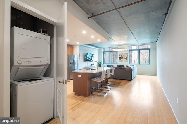 interior space with stacked washer and clothes dryer and light hardwood / wood-style flooring