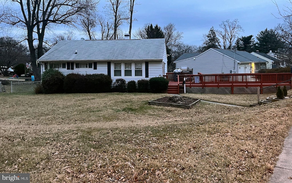 back of property featuring a deck and a lawn