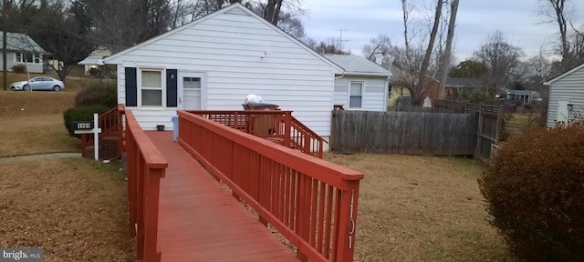 rear view of property featuring a wooden deck and a lawn