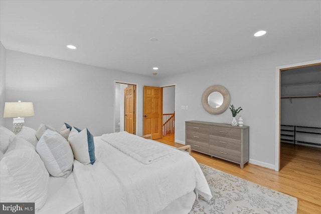 bedroom with a walk in closet and light hardwood / wood-style flooring