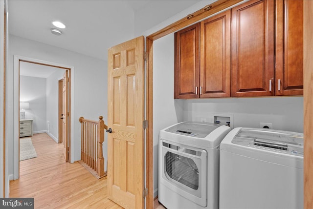 clothes washing area featuring independent washer and dryer, cabinets, and light wood-type flooring