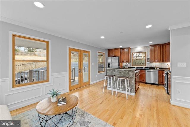 kitchen with a kitchen island, a kitchen breakfast bar, ornamental molding, stainless steel appliances, and french doors